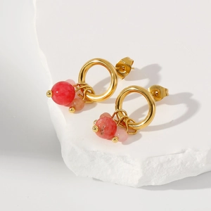 Dettaglio di orecchini in oro 18k con perline rosa e rosse su pietra bianca