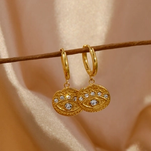 Detailed macro view of 18k gold evil eye earrings with zircon inlay on silk background
