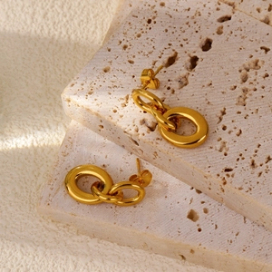 Macro detail of high-polish gold hollow double-ring earrings on decorative stones