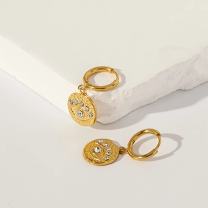 Macro detail of 18k gold plated evil eye earrings with zircon on white stone