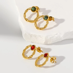 Detail view of 18k gold earrings with twisted rope frames and emerald green gemstones