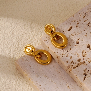 Detailed view of polished gold double hoop earrings placed on a natural stone base