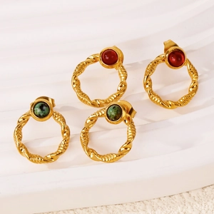 Detailed macro of vintage 18k gold twisted hoop earrings with red and green gemstones