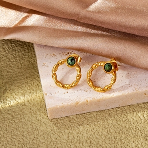 Detailed close-up of 18k gold vintage emerald earrings on rose gold silk fabric background