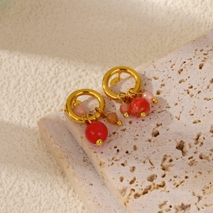 Dettaglio di orecchini a cerchio in oro 18 carats con perle rosse e rosa su base in pietra
