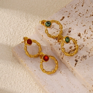 Detailed macro of gold twisted frame earrings with red and green gemstone inlays