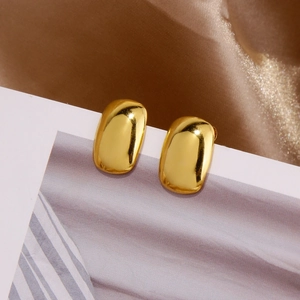 Macro shot of minimalist gold square stud earrings with high mirror-polished finish