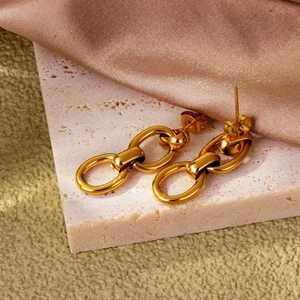 Élégantes boucles d'oreilles triple maillon dorées sur un fond de présentation luxueux