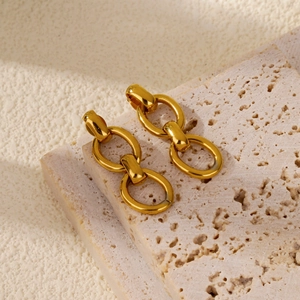 Détail de boucles d'oreilles doubles anneaux dorés sur fond de pierre texturée
