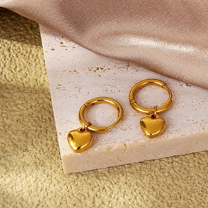 Minimalist gold heart dangle hoop earrings displayed on elegant marble and satin fabric