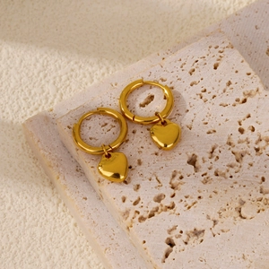 Detailed view of polished golden heart hoop earrings on elegant travertine stone