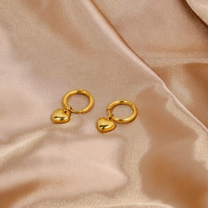 Close-up of golden heart earrings with polished finish on elegant silk background