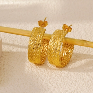 Macro shot of 18k gold C-shape hoop earrings with vintage herringbone texture