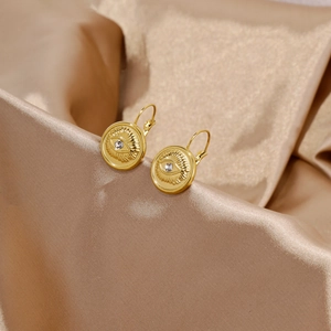 Vue macro de boucles d'oreilles œil porte-bonheur en or 18k et zircon sur du satin