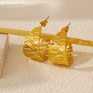 Detailed close-up of C-shaped golden leaf earrings with elegant bark texture and 18K finish