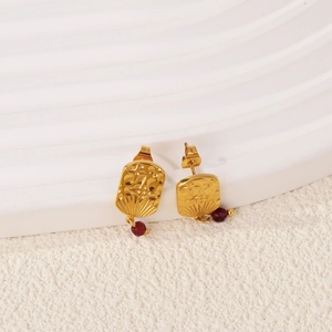 Detail of 18k gold earrings with rectangular textured plate and red ruby bead