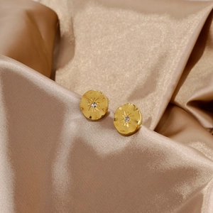 Détails de boucles d'oreilles 18k or martelé avec zircons en forme de fleur sur satin soyeux