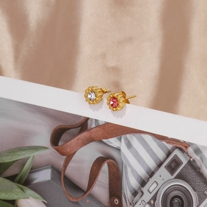 Detailed macro view of 18k gold sunflower earrings with white and pink zircon crystals