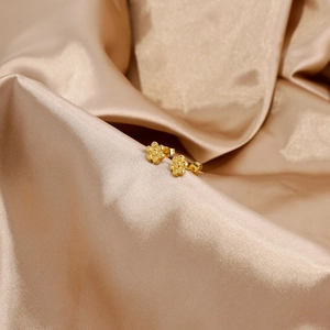 Dettaglio di orecchini a lobo a forma di girasole dorato su seta, acciaio inox 18k