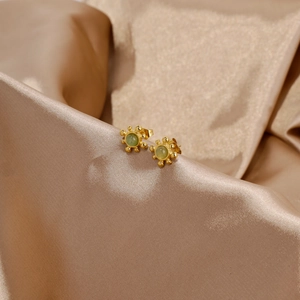 Vue détaillée d'une boucle d'oreille tournesol dorée avec pierre verte sur soie