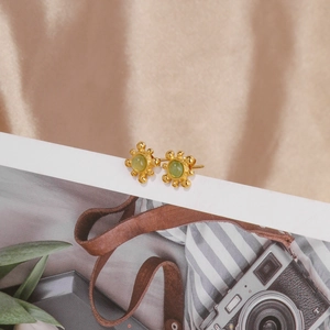 Détail de boucles d'oreilles vintage dorées avec pierres précieuses vertes rondes