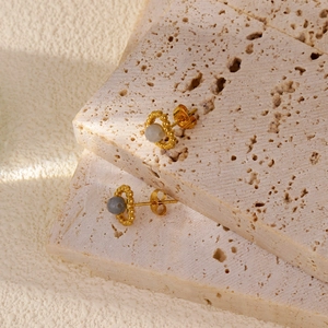 Détail macro de boucles d'oreilles dorées avec pierres blanches sur fond en pierre