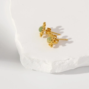 Vue macro d'une boucle d'oreille en or avec pierre vert clair sur une pierre blanche