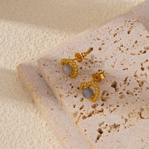 Boucles d'oreilles cœur en or avec pierre blanche sur un support en pierre