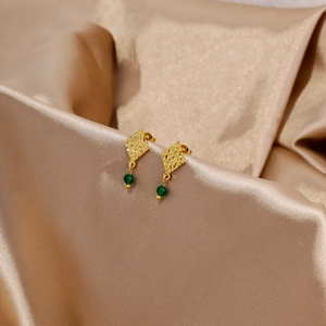 Dettaglio di orecchini a rombo dorati con texture martellata e pendente con perla verde