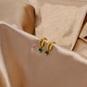 Detail of 18k gold seashell earrings with green agate bead on silk fabric background