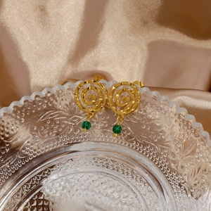 Close-up of gold spiral earrings with green malachite beads on gold silk background