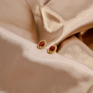 Detail of vintage 18k gold earrings with red ruby gemstone on luxury silk fabric