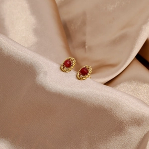 Macro detail of vintage 18k gold earrings with oval rubies and twisted rope edge