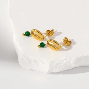 Detailed macro view of 18k gold shell earrings with dark green acrylic gemstone beads