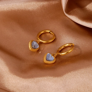 Detail of 18k gold heart earrings with light blue crystal on brown satin fabric