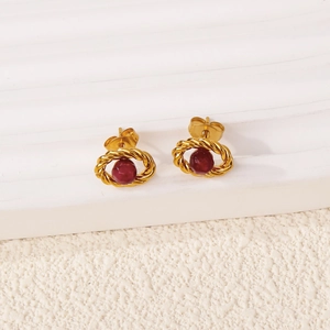 Detailed macro view of 18k gold vintage earrings with red ruby gemstone in rope texture