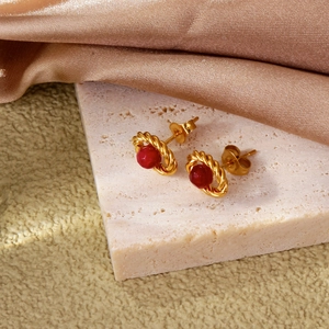 Macro shot of 18k gold twisted bezel earrings with oval ruby red bead and vintage finish