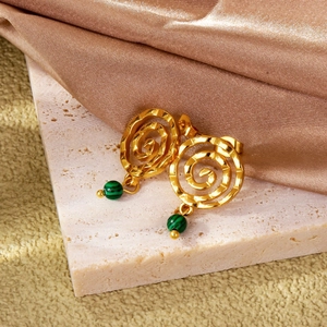 Detail of 18k gold spiral earrings featuring a green malachite bead on a stone stand