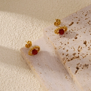 Detailed close-up of 18k gold vintage earrings with red ruby beads on a travertine stone