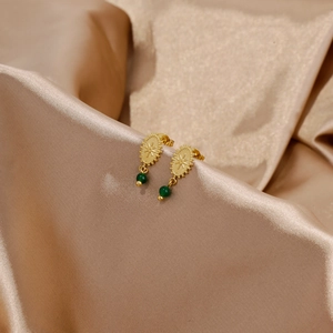 Detalle de pendientes de sol bañado en oro de 18 quilates con cuentas verde esmeralda en seda