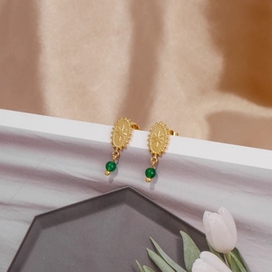 Detalle de pendientes vintage de oro 18k con cuenta esmeralda y disco solar grabado