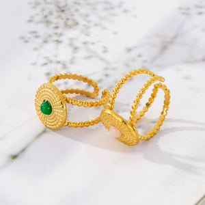 Close-up of vintage C-shaped rings with green and pink gemstones and gold metal texture