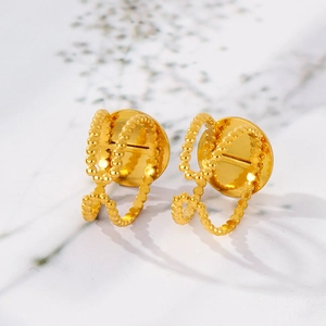 Close-up of golden earrings with circular stud and beaded double hoop texture