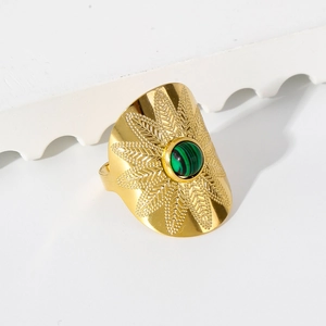 Détail macro d'une bague vintage dorée avec gravures de feuilles et pierre verte centrale