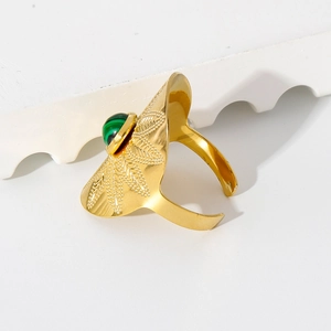 Gros plan d'une bague dorée avec texture en éventail et incrustation de malachite verte