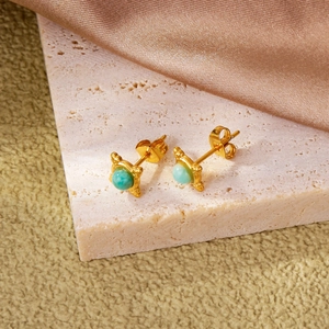 Exquisite gold clover stud earrings with round light blue gemstones on pink stone base