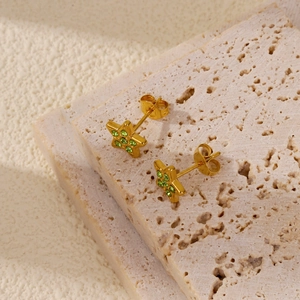 Makroansicht goldener Pentagramm-Ohrringe mit grünen Kristallen auf Steinsockel