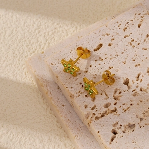 Makro-Detail von sternförmigen Goldohrringen mit lebhaften smaragdgrünen Edelsteinen