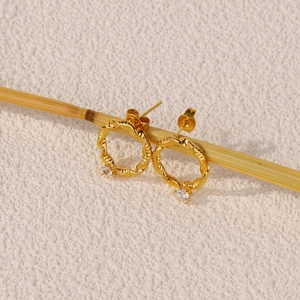 Λεπτομέρεια από στριφτά σκουλαρίκια 18k χρυσού με στρογγυλές πέτρες ζιργκόν