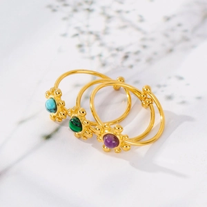 Detailed macro view of three 18K gold open rings with turquoise, malachite and amethyst stones
